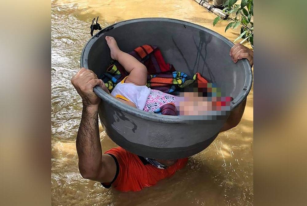 Seorang bapa membawa anaknya menggunakan bekas plastik semasa meredah air banjir di Wilayah Cagayan. - AFP