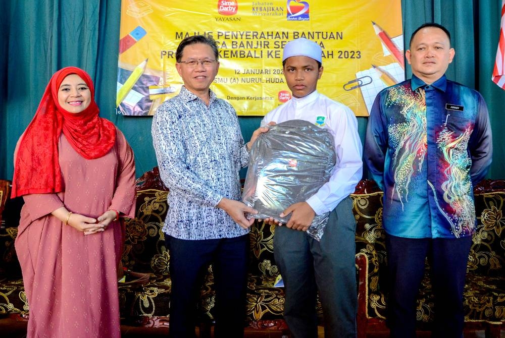 Said (dua dari kiri) menyerahkan sumbangan beg sekolah kepada pelajar pada Majlis Penyerahan Bantuan Pasca Banjir sempena Program Kembali Ke Sekolah 2023 di SMU Nurul Huda pada Khamis. - Foto Bernama