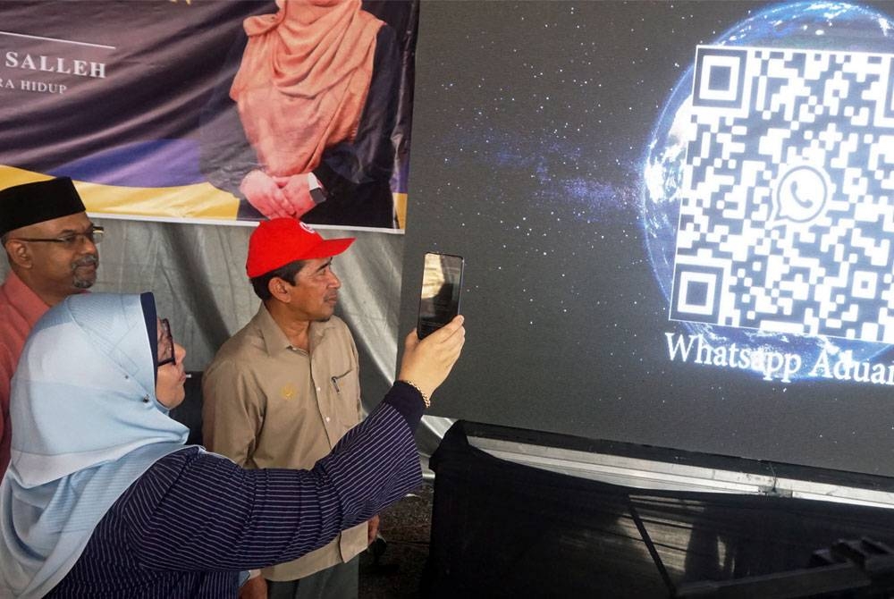 Fuziah (kiri) mengimbas QR Code saluran aduan melalui aplikasi WhatsApp pada Majlis Pelancaran Peremajaan Semula Saluran Aduan Kepenggunaan KPDN di Kompleks Belia dan Sukan pada Khamis. - Foto Bernama