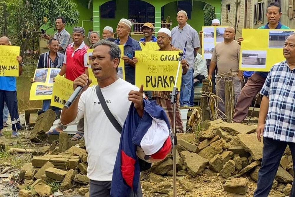 Mohd Nazan mendendangkan lagu ciptaannya sebagai luahan rasa kecewa terhadap banjir luar biasa yang melanda Rantau Panjang semasa perhimpunan aman di Kampung Tersang, Rantau Panjang pada Jumaat.