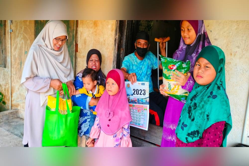 Salmiah (kiri) ketika berkunjung dan menyampaikan bantuan ke kediaman keluarga terbabit di Kampung Chengal pada Khamis.