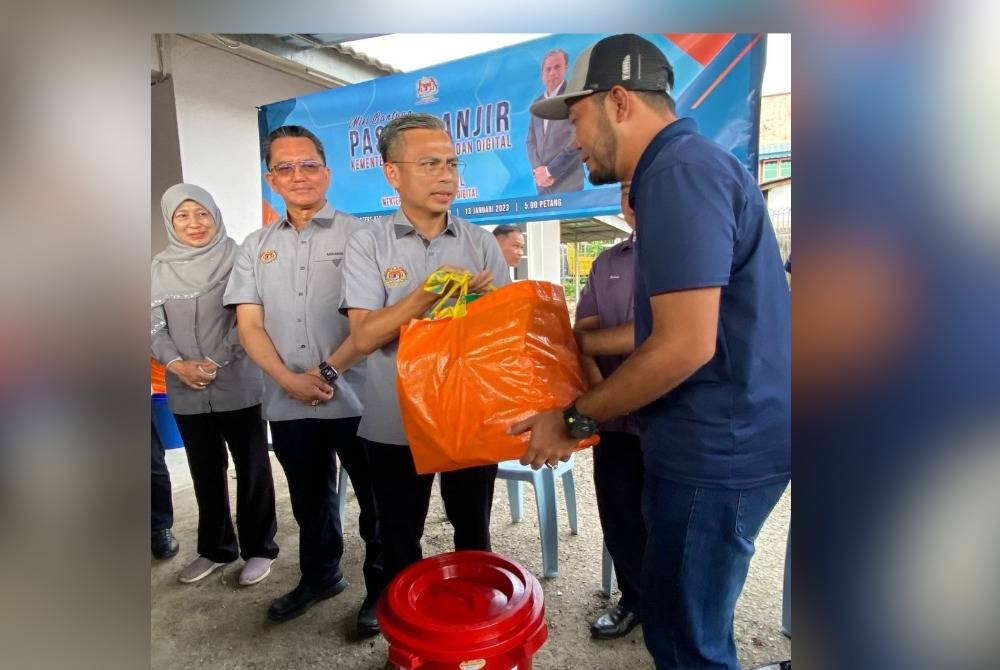 Ahmad Fahmi (tiga dari kiri) menyampaikan sumbangan banjir kepada kakitangan KKD Kelantan yang terjejas banjir di Kota Bharu pada Jumaat.