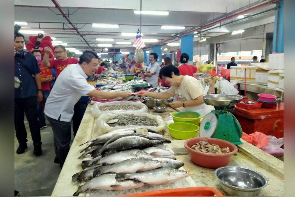 Kor Ming mengedarkan angpau kepada peniaga Pasar Besar Ipoh pada Sabtu.