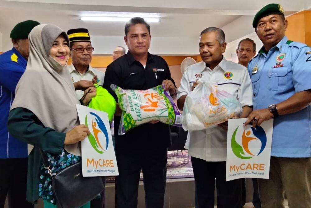 Zambery (tiga dari kanan) menyampaikan bantuan kepada pesara tentera terlibat banjir di Masjid Baiturrahman, Kampung Gual Nering pada Sabtu.