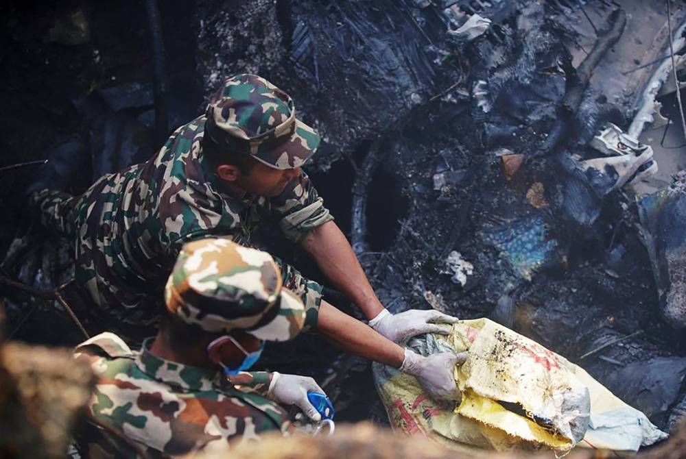 Anggota penyelamat memeriksa lokasi nahas pesawat di Pokhara. - Foto AFP