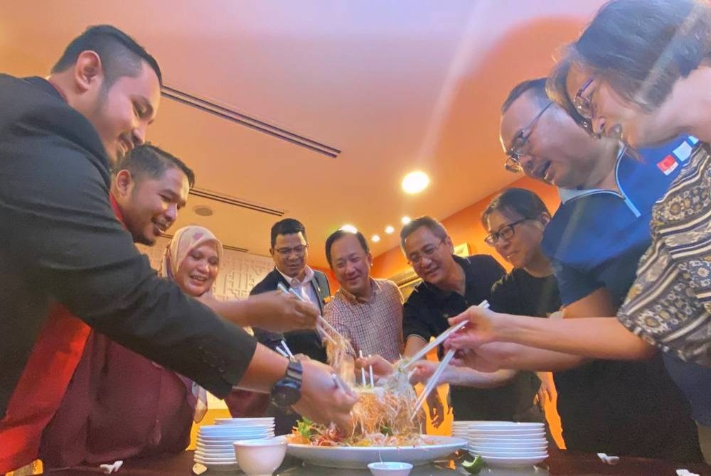 Wui Chong (dua dari kanan) bersama Majidah (tiga dari kiri) dan Bahrun Ismara (empat dari kiri) menggaul yee sang semasa meraikan sambutan Tahun Baharu Cina anjuran Hotel Perdana bersama Kemudi di Kota Bharu.