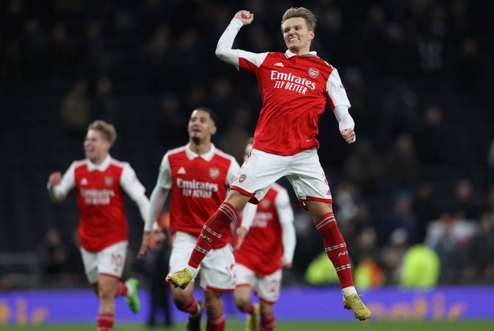 Odegaard (kanan) meraikan jaringan kedua Arsenal ketika berdepan Tottenham dalam aksi liga di London. - Foto AFP