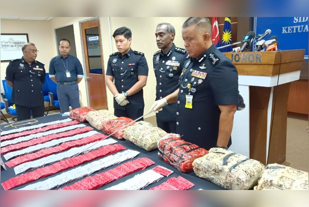 Kamarul Zaman (kanan) menunjukkan dadah yang dirampas daripada sindiket pengedaran dadah, selepas sidang akhbar di IPK Johor, Johor Bahru, pada Isnin.