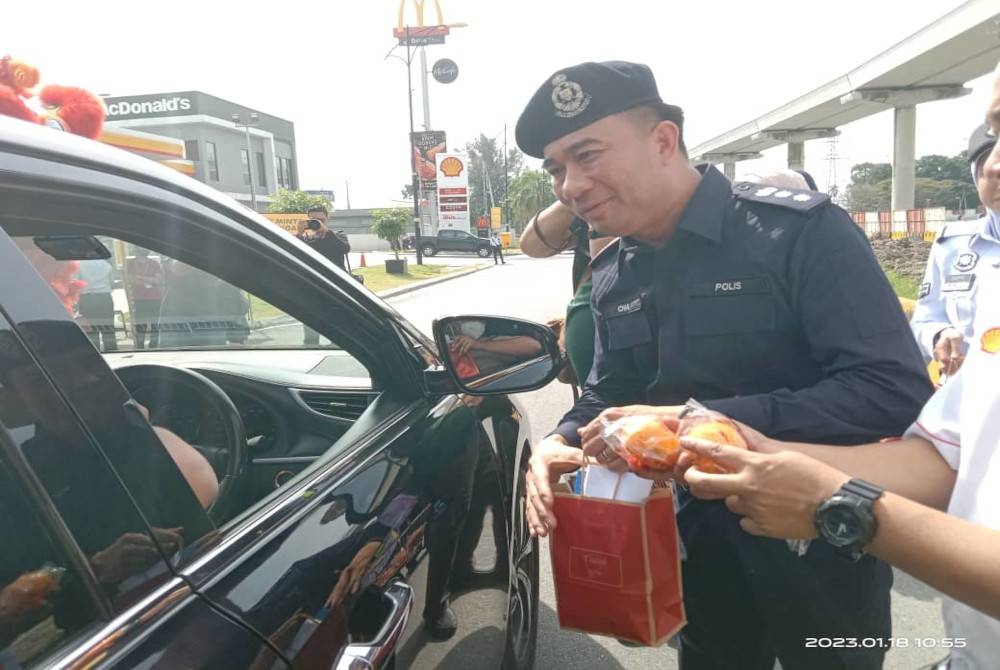 Hoong Fong menyerahkan cenderahati kepada pengguna jalan raya selepas program Op Selamat peringkat IPD Klang Selatan di Bandar Botanik Klang, Jalan Klang-Banting, Klang pada Rabu.