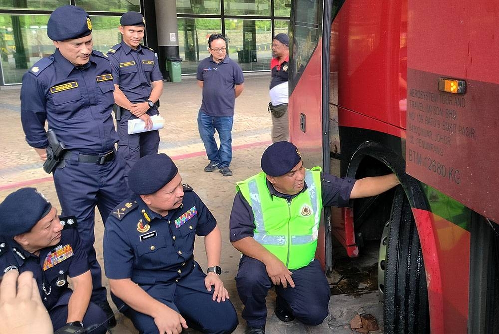 Kamarul Iskandar (duduk, tengah)memerhati pemeriksaan ke atas tayar bas yang dijalankan penguat kuasa JPJ Pahang sempena Pelancaran Kempen Keselamatan Jalan Raya Tahun Baharu Cina 2023 peringkat negeri Pahang di TSK pada Rabu.