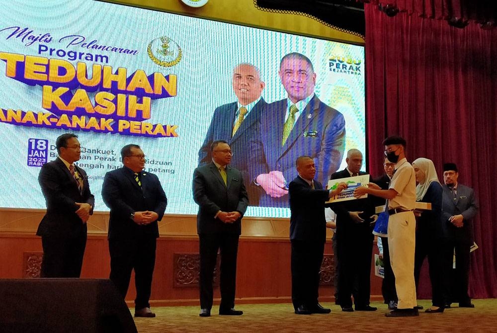 Saarani (empat dari kiri) menyampaikan sumbangan kepada pelajar terlibat ketika menyempurnakan Majlis Pelancaran Program Teduhan Kasih Anak-Anak Perak di Dewan Bankuet, Bangunan Perak Darul Ridzuan pada Rabu.