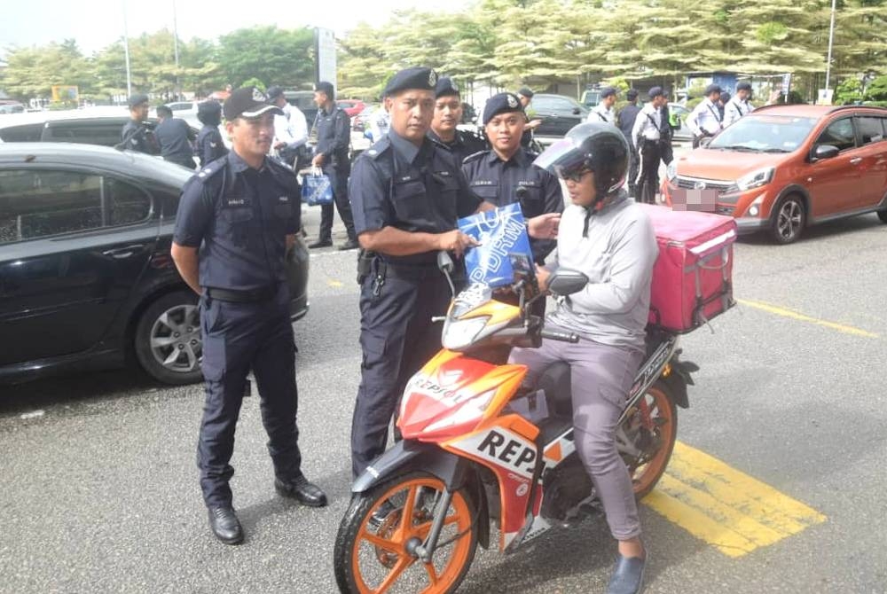 Timbalan Ketua Polis Daerah Kemaman, Deputi Superintendan Wan Muhamad Wan Ja'afar menyerah cenderahati kepada pengguna jalan raya pada Ops Selamat 19 Sempena Tahun Baharu Cina di Bandar Chukai, Kemaman pada Rabu.