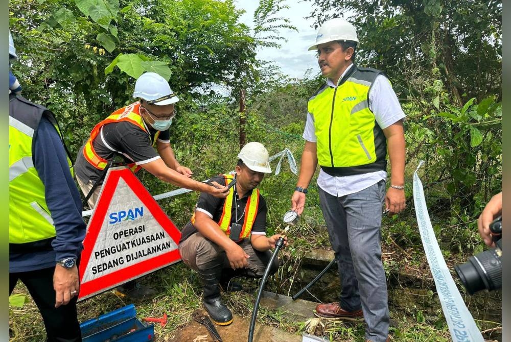 Mohd Fazil (kanan) menunjukkan penyambungan air secara tidak sah milik SAINS di lokasi serbuan di Mantin, di sini pada Rabu. - Foto Facebook Pusat Khidmat Pelanggan SAINS