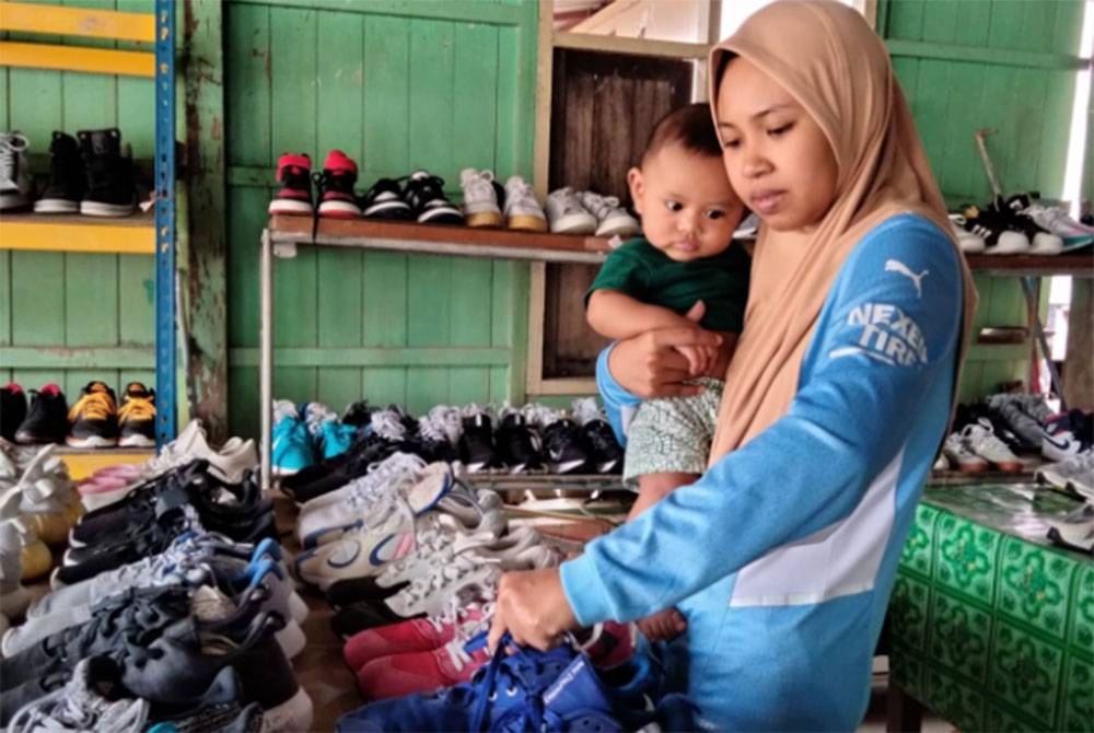 Nadzirah menunjukkan kasut yang dijual di rumah keluarganya.