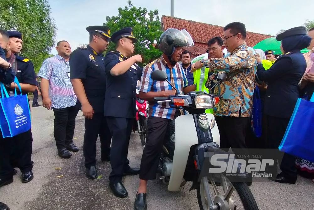 Sulaiman (kiri) memakaikan jaket keselamatan kepada seorang penunggang motosikal sempena pelancaran Majlis Keselamatan Jalan Raya (MKJR), Kempen Keselamatan Jalan Raya dan Ops Tahun Baharu Cina Tahun 2023 Peringkat Negeri Melaka di Ayer Keroh di sini, pada Khamis.