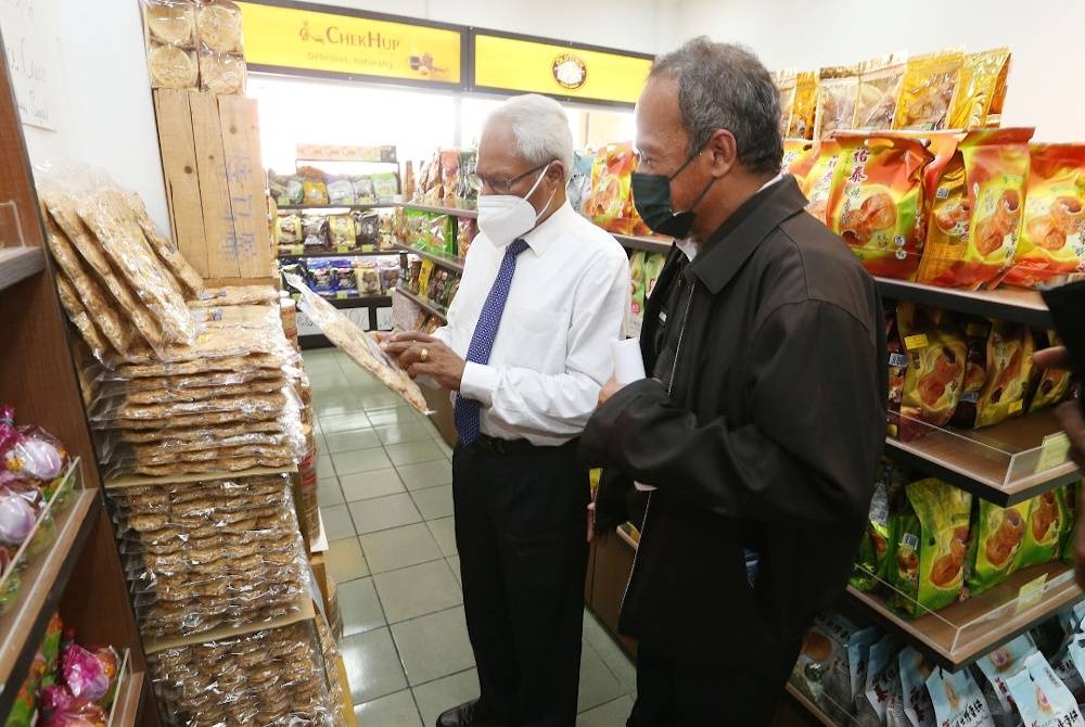 Sivanesan (kiri) memeriksa label produk makanan yang dijual di di sebuah premis di Ipoh pada Khamis sempena sambutan Tahun Baharu Cina.