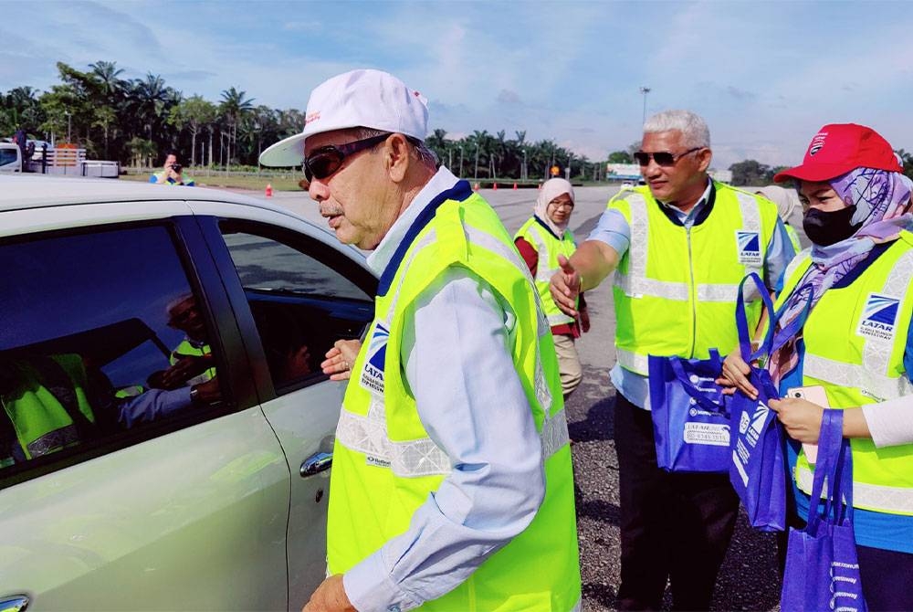 Ahmad Fuad (dua dari kanan) menyerahkan cenderahati kepada pengguna jalan raya pada Kempen Keselamatan Jalan Raya di Plaza Tol Ijok pada Jumaat.