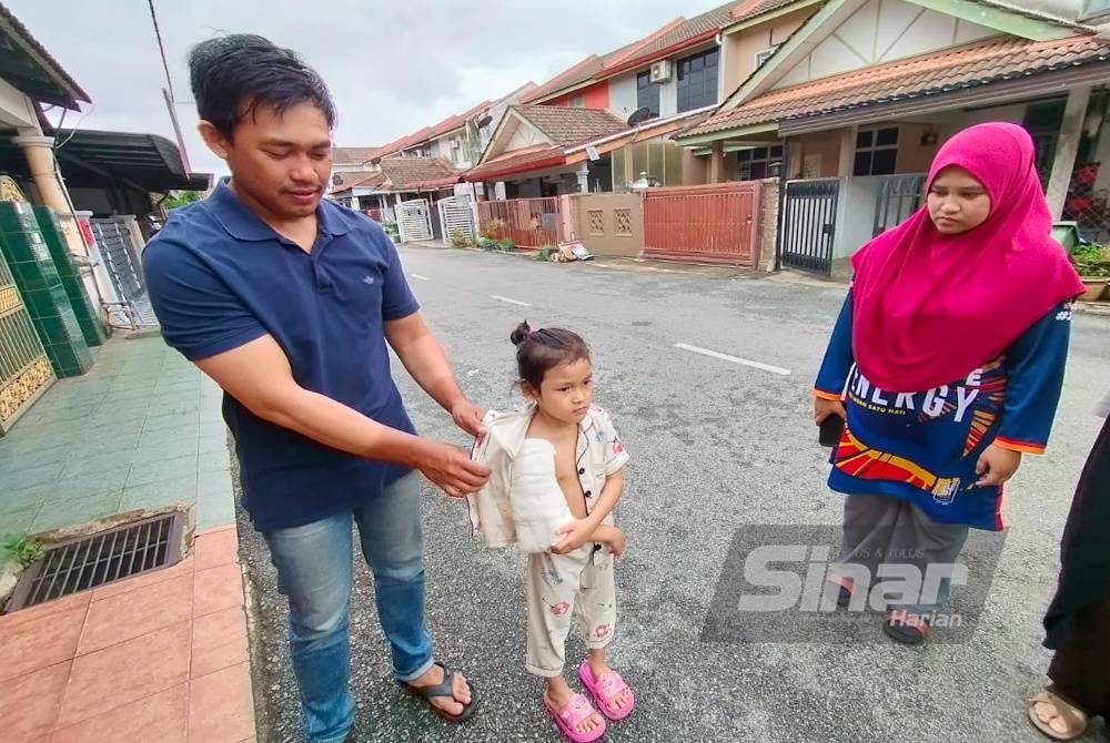 Zamarul Nizar (kiri) menunjukkan tangan kanan anaknya yang patah ketika ditemui di rumahnya di Taman Balok Baru pada Jumaat.