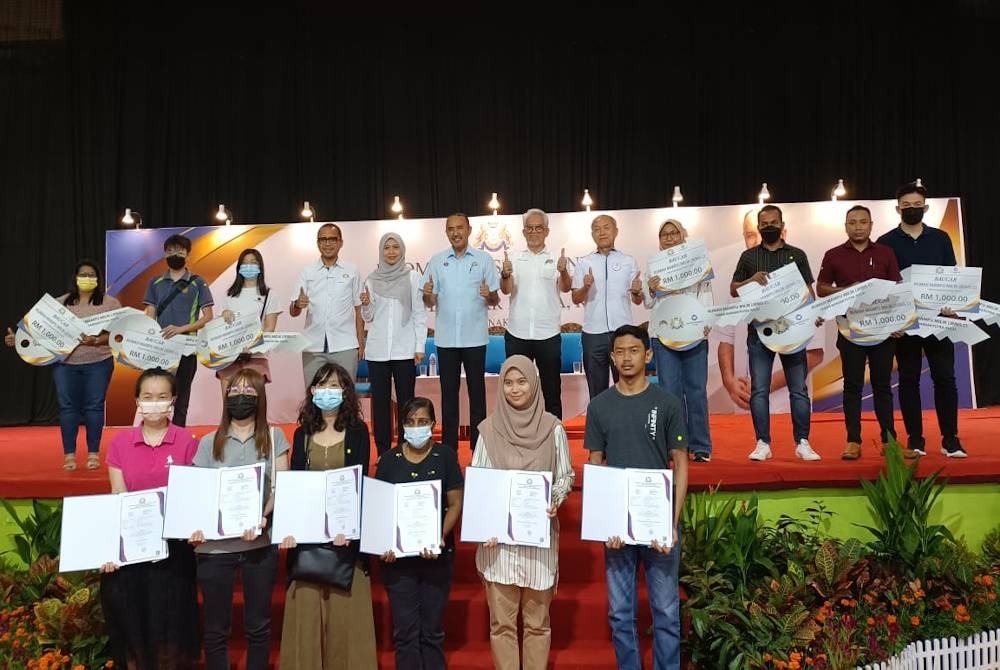 Mohd Jafni (enam dari kiri) merakam kenangan bersama penerima sijil selepas Program J-Home One Stop Centre Rumah Mampu Milik Jenis C Taman Bandar Putra di Dewan Bandar Putra, Kulai, pada Jumaat.