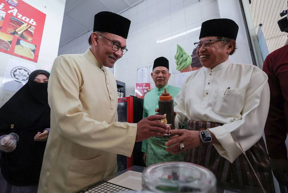 Anwar (dua dari kiri) dan Abang Johari Tun Openg (kanan) mencuba bakat membuat aiskrim gula apong ketika hadir pada Program Jelajah Kerajaan Perpaduan-Kenduri Rakyat di Kubah Ria pada Jumaat. - Foto Bernama