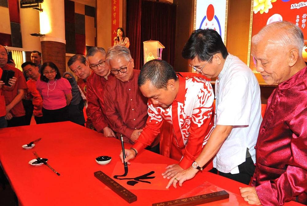 Onn Hafiz (tiga dari kanan) mencuba seni kaligrafi dalam Majlis Ramah Mesra dan Muhibah Sempena Sambutan Tahun Baharu Cina di Wisma Tiong Hua, Johor Bahru pada Ahad.