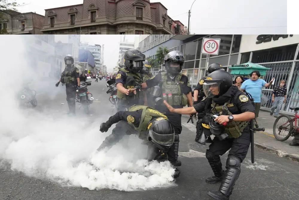 Pegawai polis mengambil tong gas pemedih mata yang dilemparkan semula ke arah mereka oleh penunjuk perasaan antikerajaan yang berarak menentang Presiden Peru, Dina Boluarte di Lima, Peru. - Foto: AP