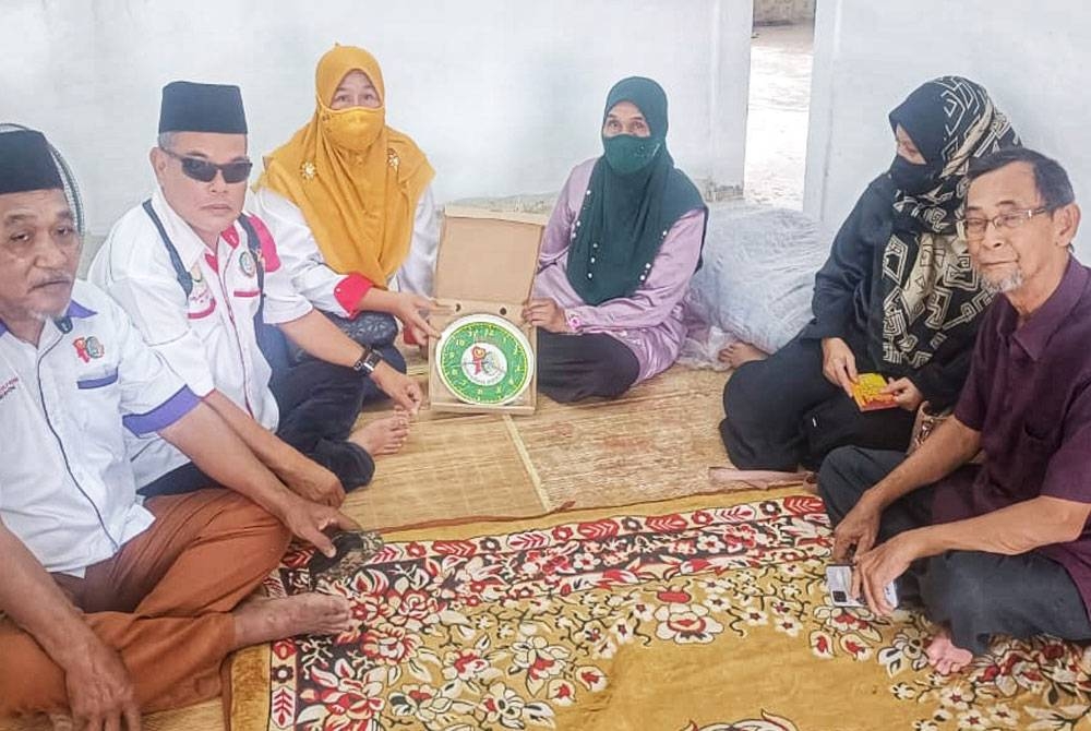 Zainab (tiga dari kanan) menerima kunci rumahnya ketika kunjungan Perkasa Parlimen Kuala Kedah pada Ahad.