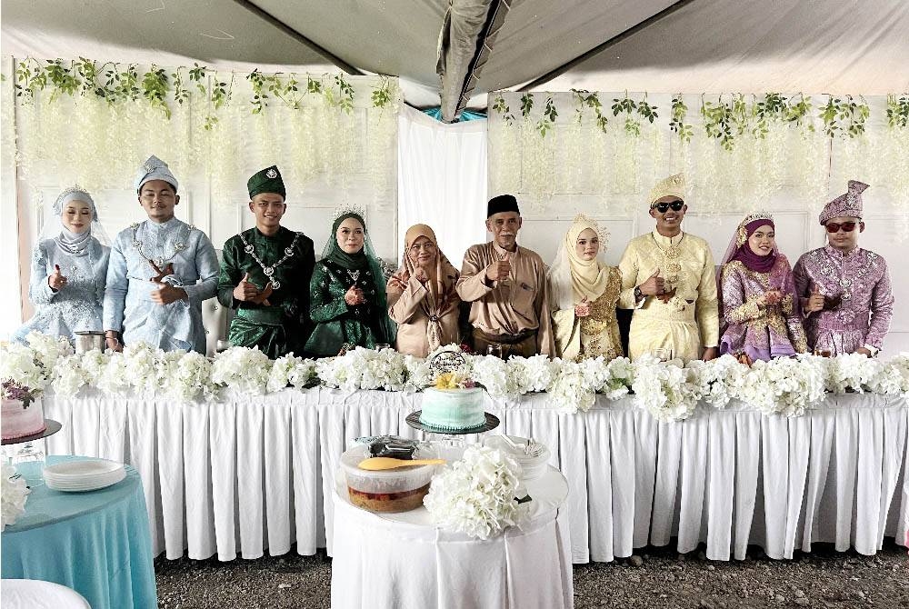 Pasangan suami isteri, Mazlan Muskon (lima, kanan) dan Misnah Sulaiman (lima, kiri) bergambar bersama empat anak mereka dan pasangan masing-masing setelah mereka memilih untuk melangsungkan majlis persandingan secara serentak di Taman Bistari, Tongkang Pechah, Batu Pahat pada Isnin. - Foto Bernama