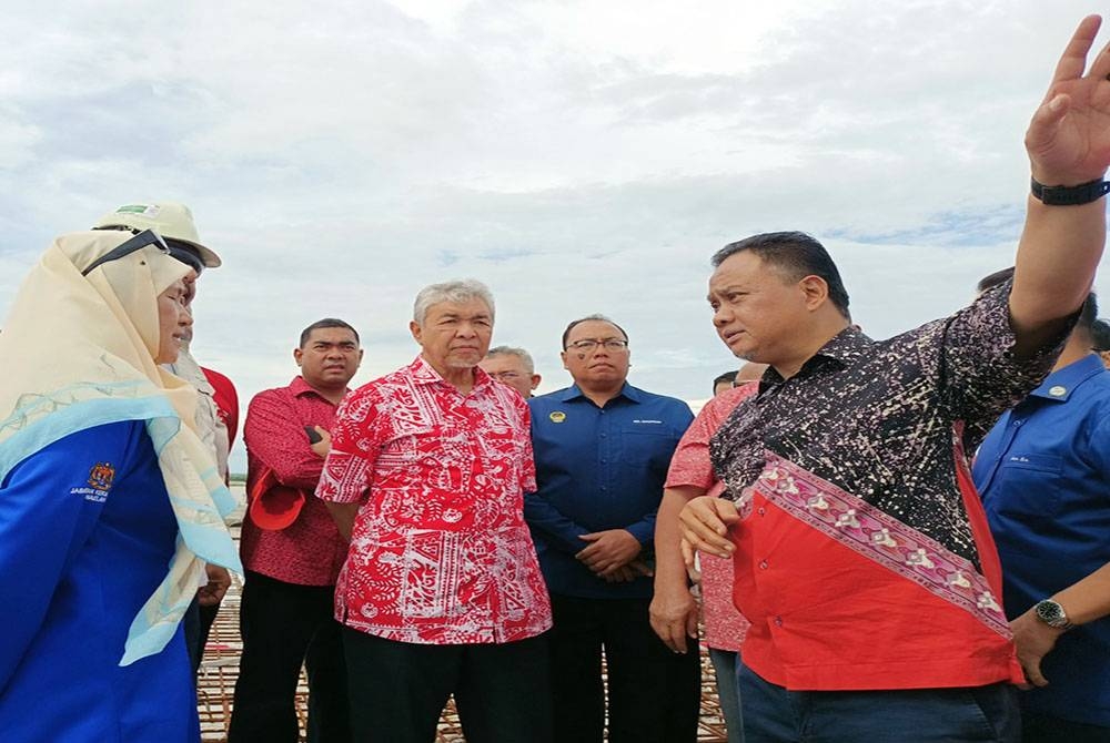 Ahmad Zahid (tengah) mendengar penerangan perkembangan pembinaan jambatan menghubungkan Bagan Datuk dan Sejagop pada Isnin.