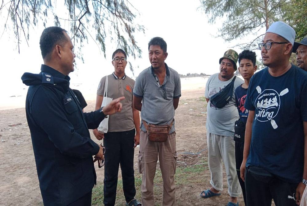 Hanizam (tengah) mendengar maklumat daripada Hussin (kiri) semasa operasi mencari anaknya di Pantai Batu Layar, Kota Tinggi, pada Isnin.