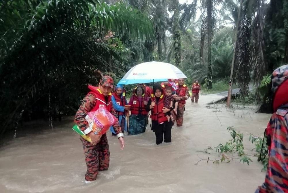 Anggota bomba membawa keluar mangsa banjir dari Kampung Paya Merah Lama.