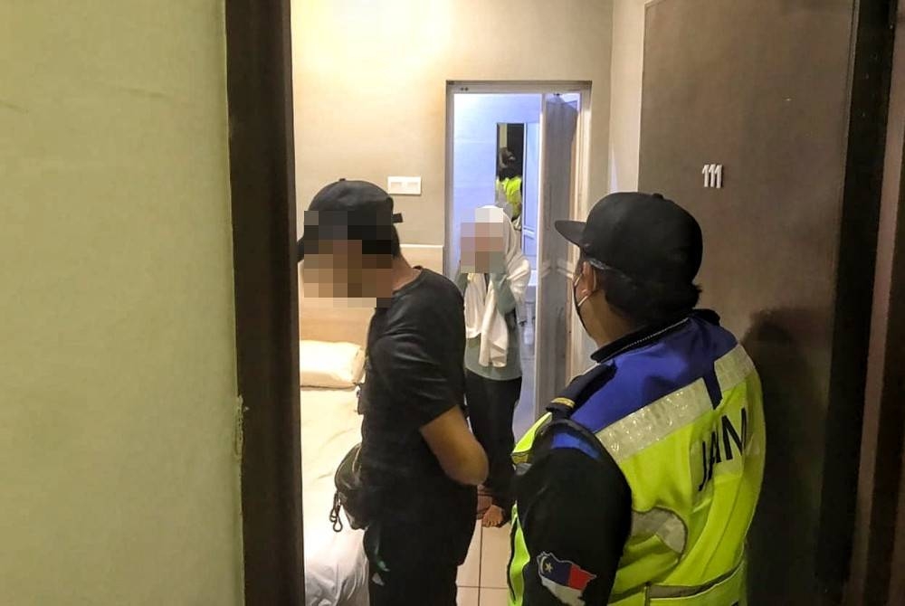 Dua pegawai penguat kuasa JAIM sedang menyoal siasat pasangan kekasih di sebuah hotel bajet di Melaka pada Ahad.