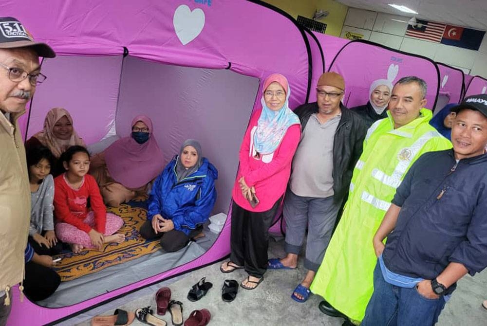 Sharifah (duduk, kanan) melawat keluarga mangsa banjir di PPS Balai Raya Kampung Bentong, Kluang, pada Selasa.