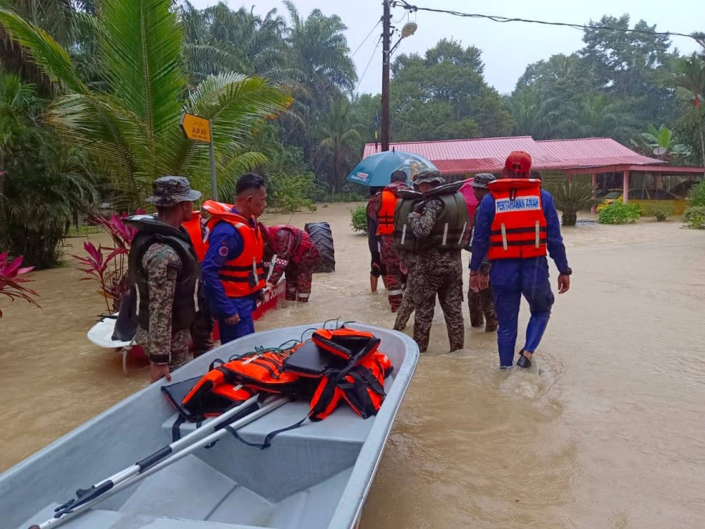 Anggota APM Johor membantu mangsa banjir untuk dipindahkan ke PPS.