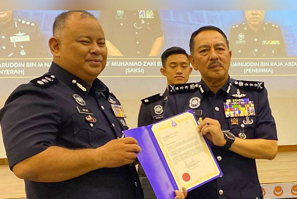 Muhamad Zaki (kanan) menyampaikan surat penghargaan kepada Mohd Nasaruddin pada Majlis Serah Terima Tugas Ketua Polis Daerah di IPD Pasir Mas pada Rabu.