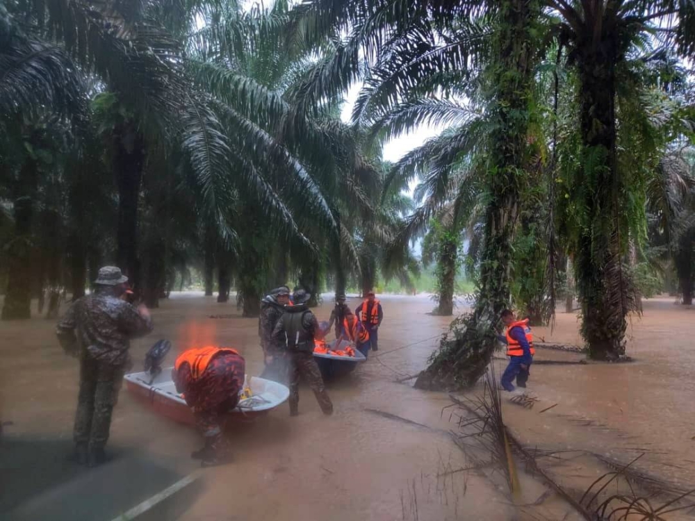 Anggota APM Johor dan tentera membantu mangsa banjir untuk dipindahkan ke PPS. Foto: APM Johor 