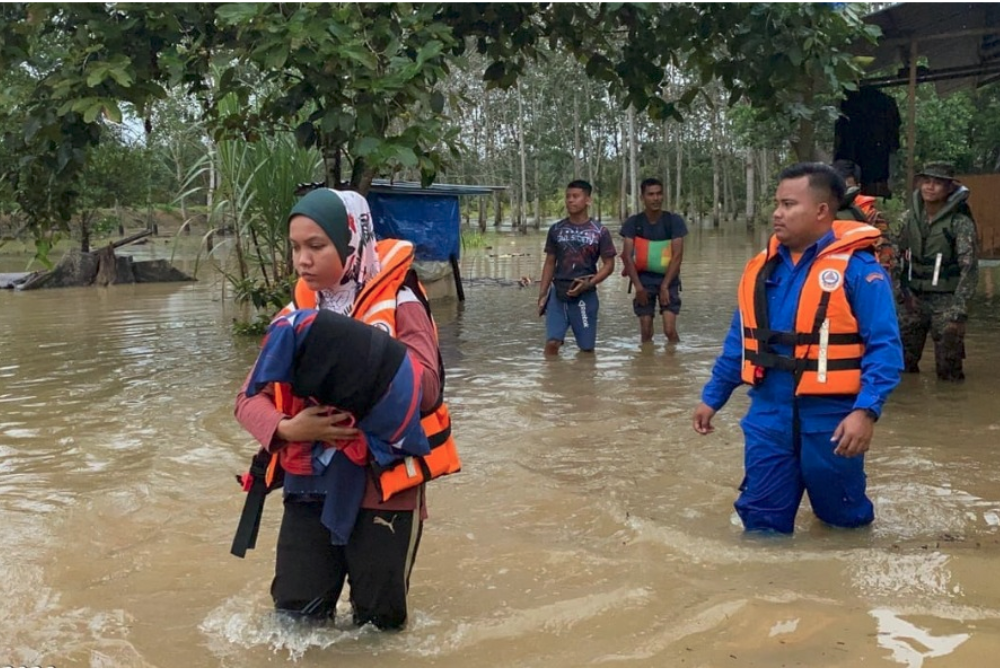 Anggota APM Johor membantu mangsa banjir di Kampung Melayu Raya ditempatkan di PPS di SK Melayu Raya, Pontian, pada Rabu. - Foto ihsan APM Johor