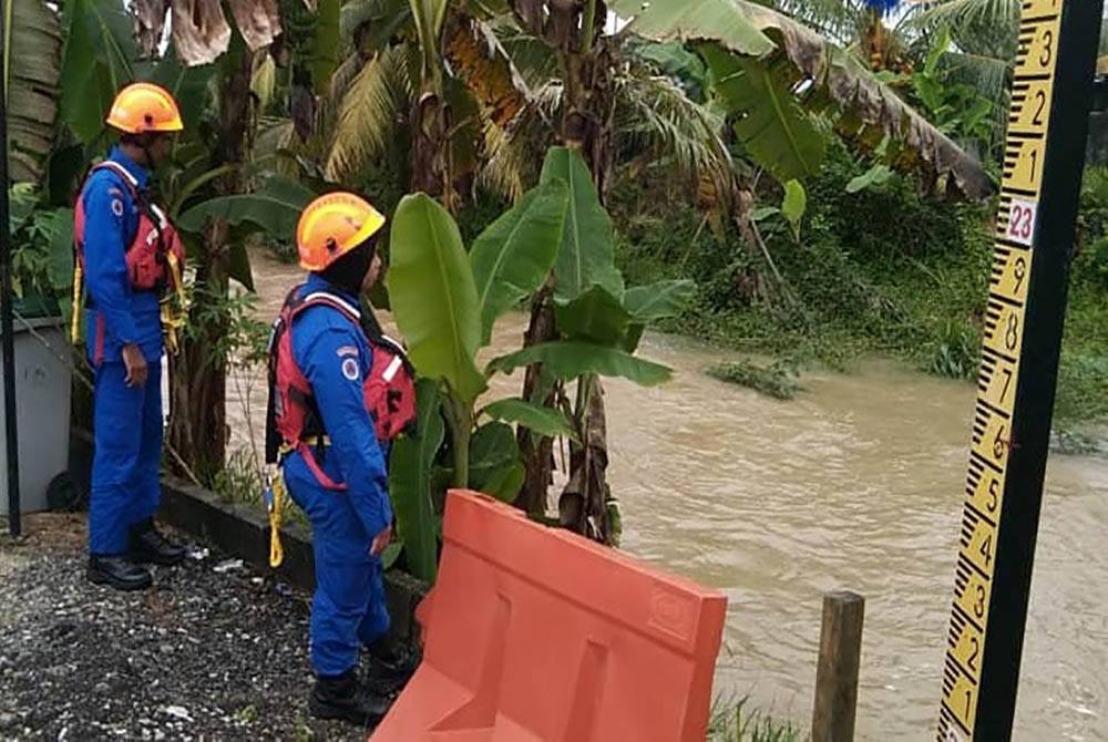 Anggota APM Johor memantau keadaan banjir di Jalan Cempaka 9, Layang Layang, Kluang pada Khamis. - Foto APM Johor