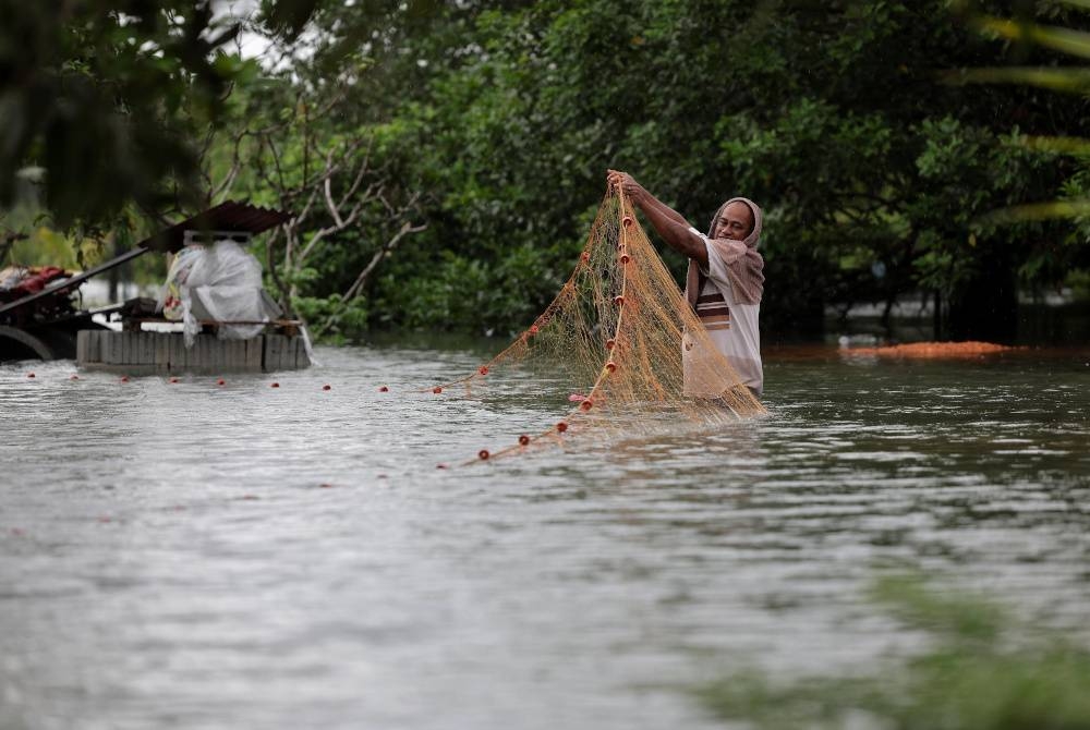 Pemandu lori, Awang Mat Yahya, 55, tidak melepaskan peluang memasang jaring di sekitar rumahya di Kampung Perpat, Tanjung Sedili yang dilanda banjir susulan hujan lebat berterusan ketika tinjauan pada Rabu. - Foto Bernama