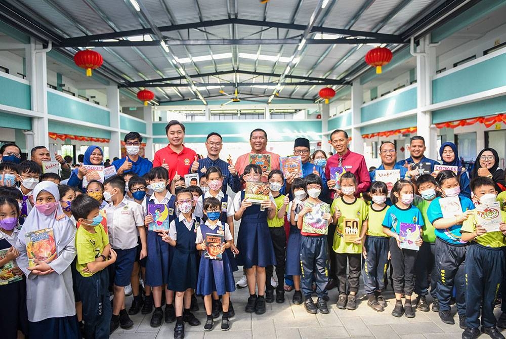 Nik Justin (tengah) bergambar dengan murid SJKC Bukit Fraser yang memegang buku sumbangan Kumpulan Karangkraf.