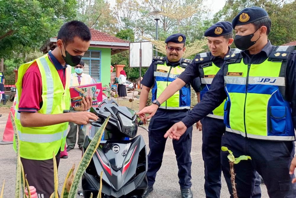 Pengarah JPJ Melaka, Muhammad Firdaus Shariff (tiga dari kanan) melihat pemeriksaan motosikal oleh salah seorang kadet JPJ sekolah ketika hadir pada Program Advokasi Keselamatan Jalan Raya di Sekolah Menengah Kebangsaan Ayer Keroh, di sini pada Jumaat. - Foto Bernama