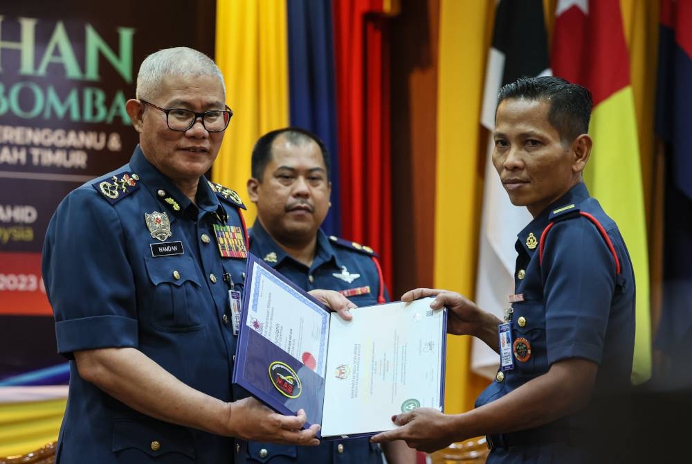 Mohammad Hamdan (kiri) menyampaikan sijil kursus 'International Life Saving' kepada anggota bomba, Nooresham Md Din pada Majlis Penganugerahan Pingat Perkhidmatan Bomba Bagi Akademi Bomba dan Penyelamat Wilayah Timur dan JBPM Terengganu di Akademi Bomba dan Penyelamat Malaysia Wilayah Timur, Wakaf Tapai, di sini pada Jumaat. - Foto Bernama