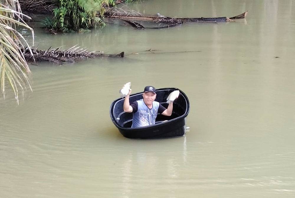 Firdaus menunjukkan ikan sungai yang diperoleh dengan memasang jaring di kawasan kebun kelapa sawit berhampiran jalan utama Batu Pahat-Mersing, Kluang, pada Jumaat.