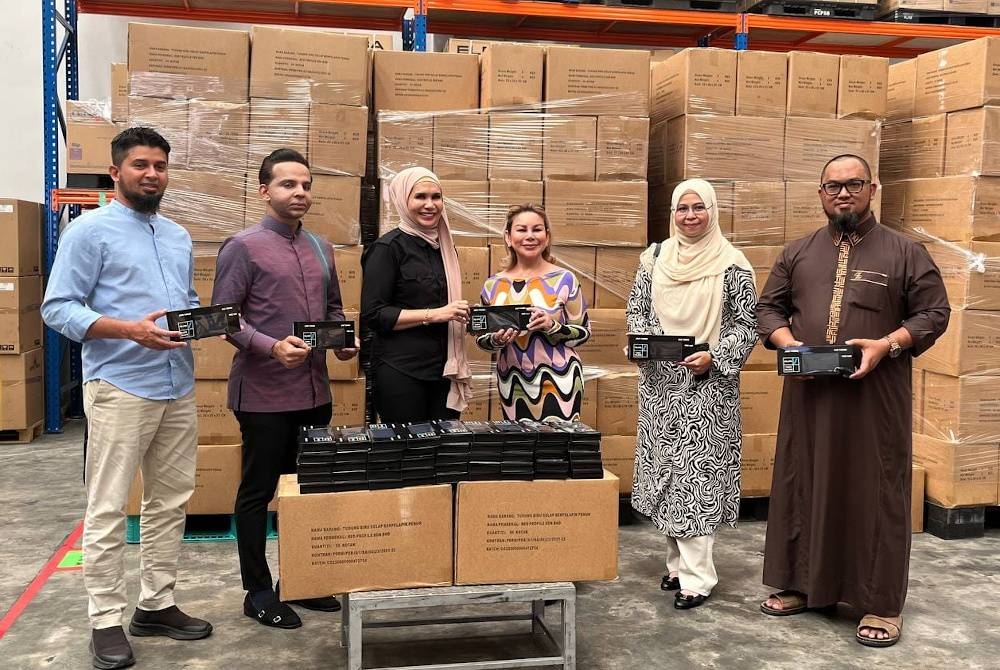 Penaung Helping Shoulder, Datuk Emma Ibrahim (tiga dari kanan) menyerahkan secara simbolik tudung kepada Illa Ruzaini (tiga kiri) pada Majlis Penyerahan Tudung di Aimanjie Distribution Center Kawasan Perindustrian Bukit Angkat di sini pada Jumaat.