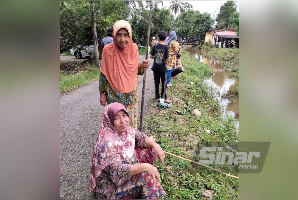 Sepiah (duduk) dan Mariam menyertai pertandingan memancing secara tradisional di Kampung Perangkap.