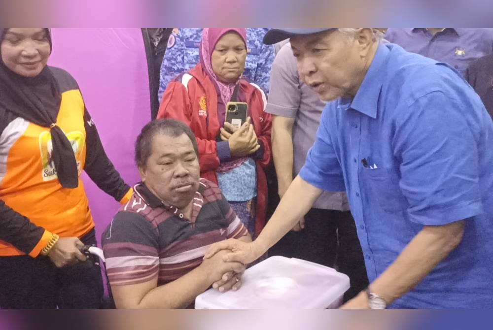 Ahmad Zahid (kanan) menyampaikan sumbangan kepada mangsa banjir di PPS Politeknik Mersing, pada Sabtu.