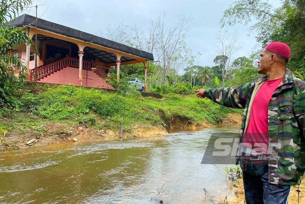 Ishak menunjukkan hakisan di tebing Sungai Tandak Liang di Kampung Tanjong Erat, Lubok Setol, Rantau Panjang.