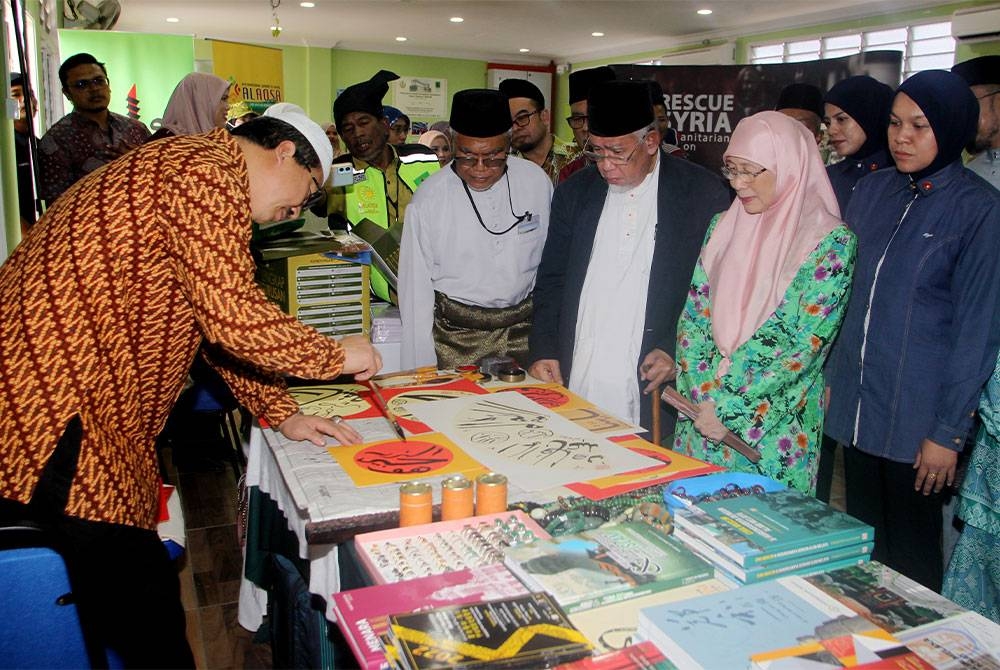 Wan Azizah (dua dari kanan) melihat seni tulisan khat oleh Yusuf Liu Baojun (kiri) ketika melawat ke pameran pada majlis perasmian Kompleks Pendidikan Baitul Ridzuan (KOBAR) dan pelancaran Sekretariat Masyarakat Madani Tambun (SMAT) anjuran MAPIM di Jalan Raja, Kampung Manjoi hari ini. Foto Bernama