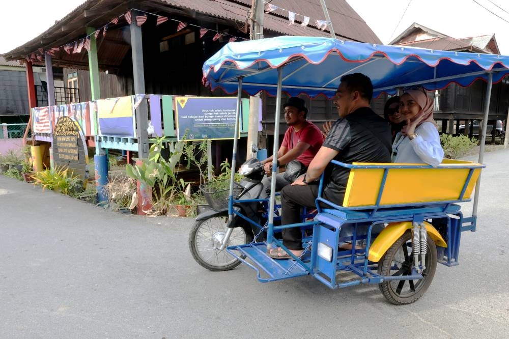 Hanya dengan bayaran RM35, pengunjung dapat menikmati keunikan persekitaran Projek DiRaja Program Transformasi Kampung Warna-Warni Seberang Ramai, Kuala Perlis di sini dengan menaiki &#039;Choley&#039; atau motosikal beroda tiga. - Foto Bernama