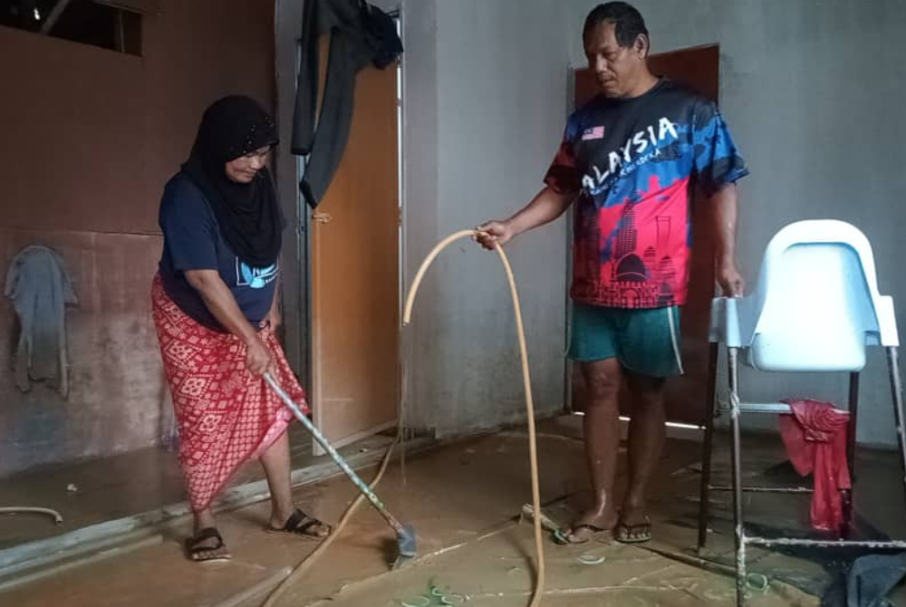 Penduduk Kampung Seberang Batu Badak, Segamat, Salam Hamid dan isteri, Siti Yatimah Awang membersihkan rumah mereka selepas banjir surut pada Selasa.